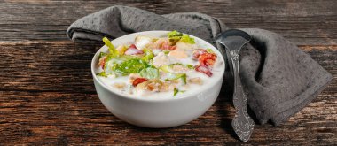 Geleneksel Rus soğuk çorbası okroshka taze patates, salatalık, domates, haşlanmış yumurta ve kefir. Düz zemin, ahşap zemin, üst manzara