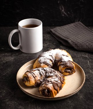 Cup of black tea, traditional chocolate pastries on a dark background, stock photo