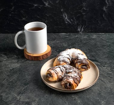 Cup of black tea, traditional chocolate pastries on a dark background, stock photo