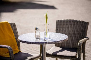Empty tables outside between lunch hours along a cobblestone alley in a European city, a veranda, a cafe