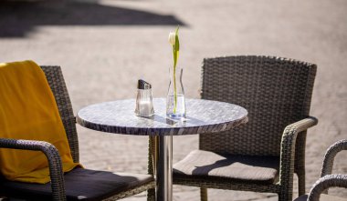 Empty tables outside between lunch hours along a cobblestone alley in a European city, a veranda, a cafe
