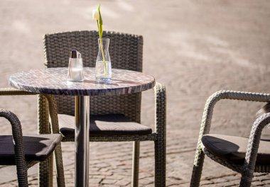 Empty tables outside between lunch hours along a cobblestone alley in a European city, a veranda, a cafe