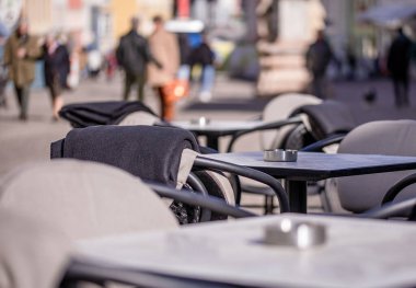 Empty tables outside between lunch hours along a cobblestone alley in a European city, a veranda, a cafe