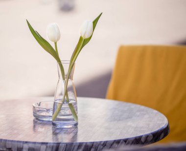 Empty tables outside between lunch hours along a cobblestone alley in a European city, a veranda, a cafe