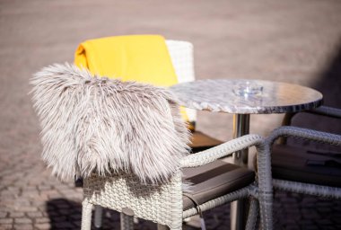 Empty tables outside between lunch hours along a cobblestone alley in a European city, a veranda, a cafe