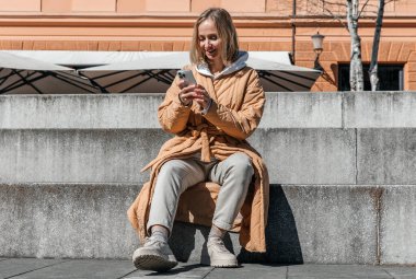 Şehirde yürüyen güzel, genç, şık bir kadın. Bahar havası, hayal kurmak ve beklemek, bir yaşam tarzı konsepti
