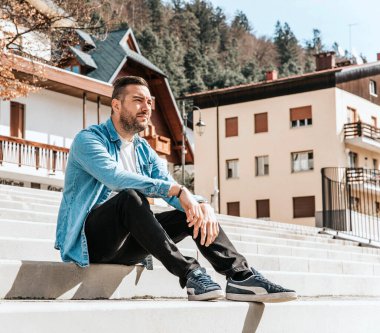 Kot ceketli yakışıklı bir hippi portresi. Sokaktaki büyük bir şehirde bir adam, yaşam tarzı konsepti.