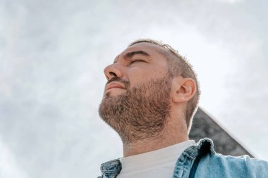 Sokakta büyük bir şehirde kot ceketli yakışıklı bir hippi portresi, yaşam tarzı konsepti.