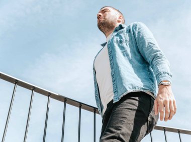 Sokakta büyük bir şehirde kot ceketli yakışıklı bir hippi portresi, yaşam tarzı konsepti.