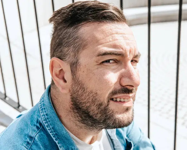 stock image Portrait of a handsome hipster man in a jean jacket in a big city on the street, a life style concept