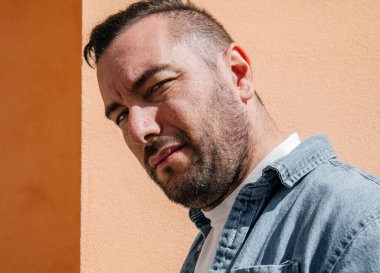 Kot ceketli yakışıklı bir hippi portresi. Sokaktaki büyük bir şehirde bir adam, yaşam tarzı konsepti.