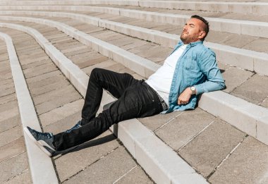 Kot ceketli yakışıklı bir hippi portresi. Sokaktaki büyük bir şehirde bir adam, yaşam tarzı konsepti.