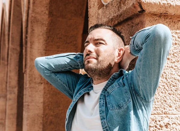 stock image Portrait of a handsome hipster man in a jean jacket. A man in a big city on the street, a life style concept