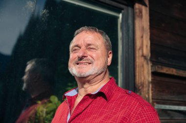 Nazik bir gülümsemesi olan yaşlı adam batan güneşin sıcaklığının tadını çıkarıyor.