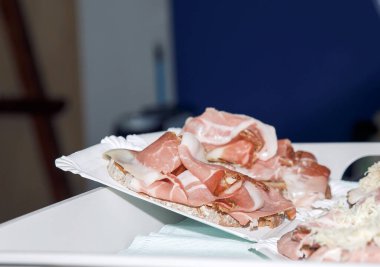 Villach, Avusturya - 07.13.2024: İtalyan prosciutto dilimleri beyaz ekmek, lezzetli ve zarif bir aperatif, her özel durum için mükemmel, bir gıda sanatları konsepti