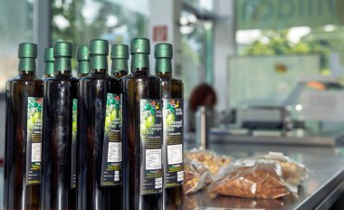 Villach, Avusturya - 07.13.2024: Marketin rafındaki zeytinyağı şişeleri atıştırmalıkların yanında, sağlıklı pişirme konsepti