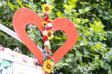 Kalp şeklinde, renkli çiçeklerle süslenmiş, açık hava yaz sahnesi, aşk ve doğa konsepti.