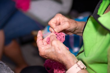 Üst düzey kadınların örgü ören ellerine pembe iplik, el işi, dikiş, odaklanma ve konsantrasyon, boş zaman aktivitesi, hobi, yaratıcılık konsepti