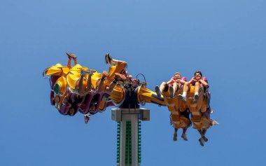 İnsanlar eğlence parkı eğlencesi, heyecan verici sürüş deneyimi, yaz günü gökyüzü manzarası, eğlenceli macera konsepti.