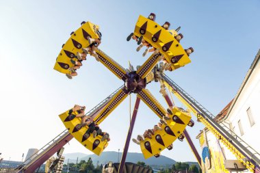 Heyecan verici eğlence parkı gezisi neşeli insanlar, canlı sarı yapı, parlak gün ışığı, açık hava eğlencesi, heyecan verici deneyim konsepti