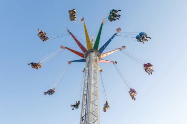 Eğlence parkında salıncakta sallanmak, uzun ve renkli bir çekim, insanlarla dans etmek, eğlence konsepti.
