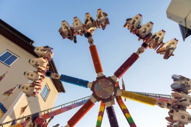 Mavi gökyüzüne karşı renkli bir gezinti, hareket halindeki sürücüler için heyecan verici bir deneyim, açık hava karnaval eğlence konsepti heyecanı