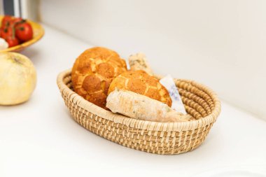 İçinde taze ekmek, gevrek somunlar ve beyaz bir yüzeyde baget bulunan sepet, ev yapımı konsept.