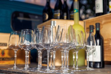 Masaya dizilmiş boş şarap kadehleri, düzgünce yerleştirilmiş cam bardaklar, arka planda şarap şişeleri, şarap tatma için kurulum, konsept.