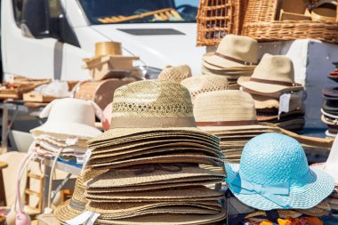 Various straw hats, colorful headwear on display at an outdoor market stall, summer accessories, fashion concept clipart