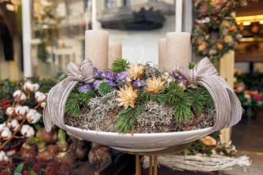 Mumlarla süslenmiş, kurumuş çiçekler, çam dalları, kurdeleler, yosunlarla düzenlenmiş, şenlikli dekoratif bir konsept.