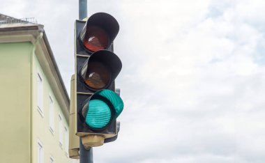 Kentsel bir ortamda yeşil trafik ışığı, açık bir gökyüzü altında ilerlemek, kavşakta sokak güvenliğini sağlamak, şehir trafiği, gündüz trafiği, altyapı ve trafik düzenlemesi kavramı için olmazsa olmaz.