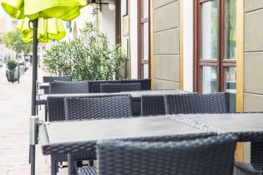 Hasır mobilyalar, açık büfe masaları ve sandalyeler, sokak restoranları, şehir yemekleri, güneşli günler, yeşil şemsiyeler, rahat atmosfer, davetkar köşeler, rahat yemekler, rahat ortam, konukseverlik endüstrisi konsepti.