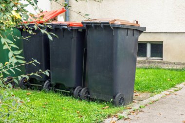 Dışarıdaki çöp bidonları, asfalt yolun yanındaki yeşil çimlerin üzerinde, bir yerleşim bölgesinde, atık yönetimi kavramı
