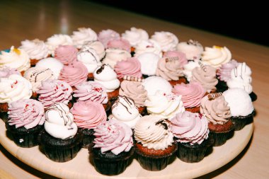 Bir kutlama etkinliğinde ahşap tabakta sergilenen çeşitli gurme kekler.