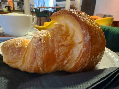 Kahve masasında yeni pişmiş kruvasan ve kahve fincanı.