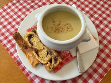 Tarçınlı kremalı çorba ve damalı masa örtüsü üzerine tatlı ekmek.