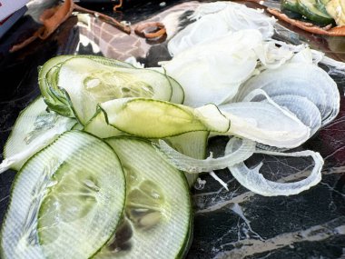 Sliced cucumbers and onions on marble surface - fresh, crisp, perfect for salads clipart