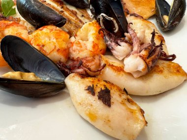 Lezzetli ızgara deniz ürünleri tabağı, midye, mürekkep balığı ve karides.