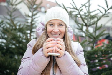 Kış harikalar diyarında sıcak içkinin tadını çıkaran bir kadın.