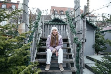 Kırsal ahşap merdivenlerde kışın keyfini çıkaran bir kadın.