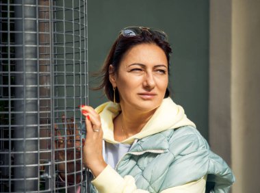 Güneş gözlüklü, kalın ceketli, güneş ışığından hoşlanan bir kadın.