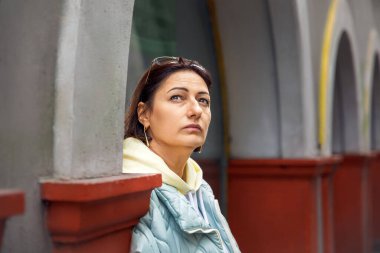 Şehir ortamında kemerli mimariyle düşünceli bir kadın.