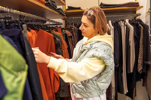 Moda bir butikte kıyafet alışverişi yapan bir kadın.
