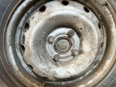 Paslı, cıvatalı ve yıpranmış metal desenli tekerlek merkezinin yakın görüntüsü.