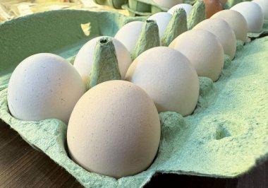 Fresh organic eggs in eco-friendly carton on wooden table. clipart