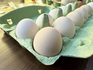 Fresh organic eggs in eco-friendly recycled cardboard carton on rustic wooden table. clipart