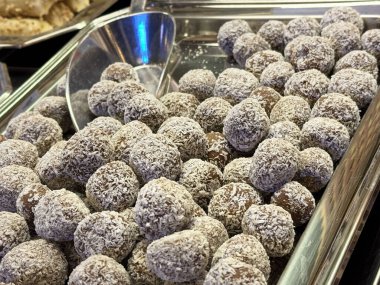 Hindistan cevizi kaplı çikolatalı trüf, tatlı büfesinde metal tepside sergileniyor..