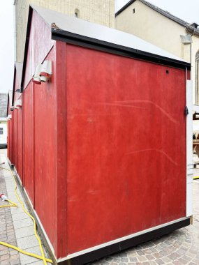 Şehir ortamında siyah çatılı kırmızı ahşap kulübe.