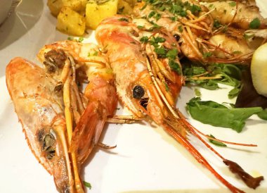 Limonlu ızgara karides ve beyaz tabakta otlar..