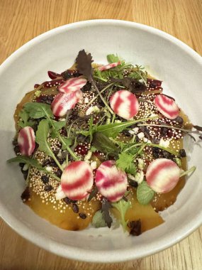 Vibrant beetroot and greens salad with quinoa and radishes in a white bowl. clipart